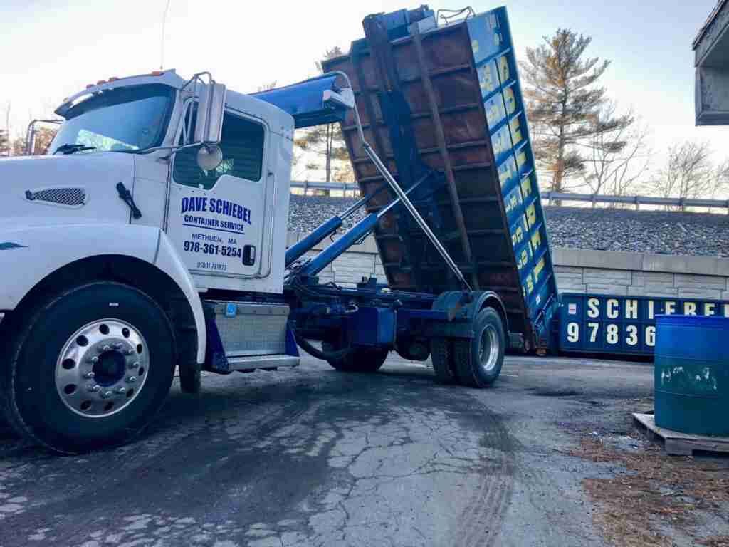 A large blue roll off dumpster being dropped off for a customer