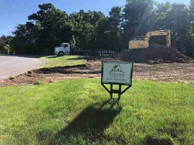 A yard that is being renovated with a roll-off dumpster parked on the lawn
