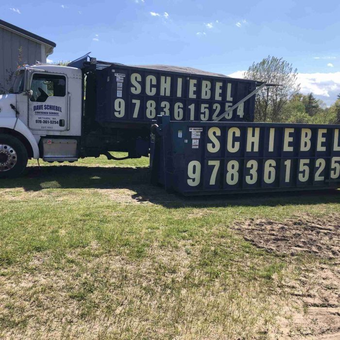 Scheibel Waste truck and dumpsters side by side on someone's yard.