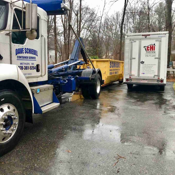 Schiebel waste truck picking up one of its yellow roll off dumpsters from a driveway