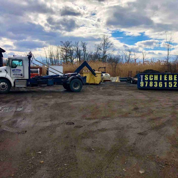 A schiebel waste truck picking up one of their large dumpster rental from a customers property