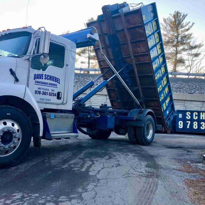 A large blue roll off dumpster being dropped off for a customer