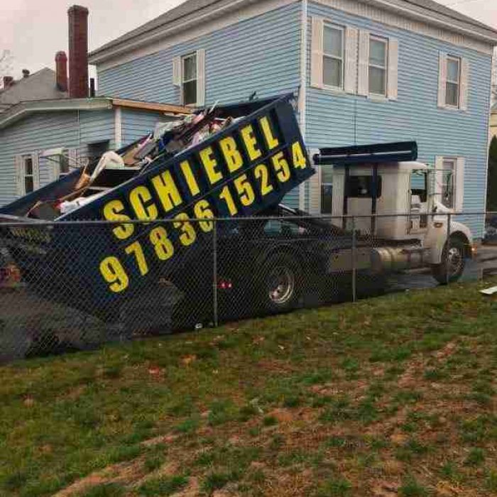 A home with a large roll off dumpster filled with trash and debris