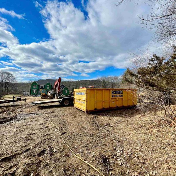 A yellow scheibel waste roll off dumpster placed at a construction site